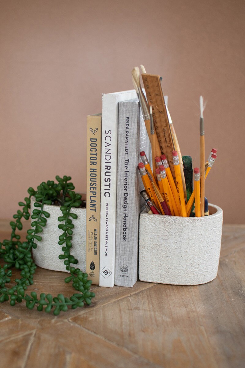 Pencil holder with pencils, books, and a plant on a wooden surface.