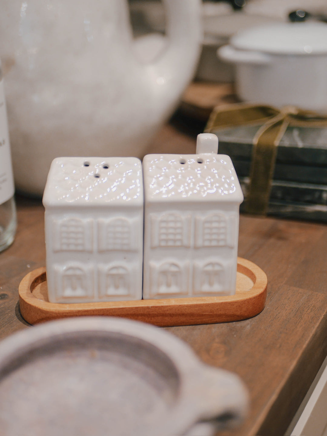 White ceramic salt and pepper shakers with a wooden base on a wooden surface.