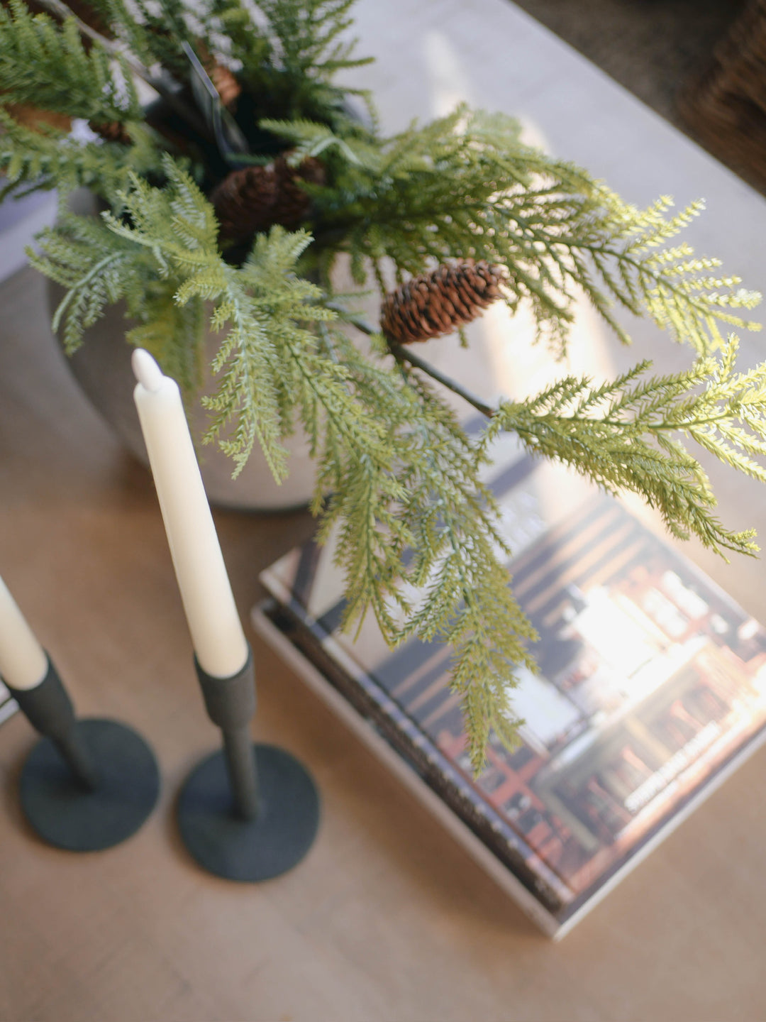 Artificial Christmas pine spray with frosted and full branches, including pine cones, in a clear vase.