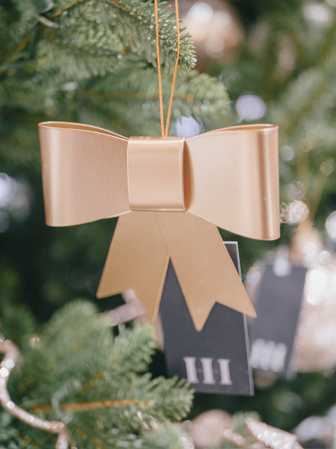 Gold bow ornament on a Christmas tree with blurred background