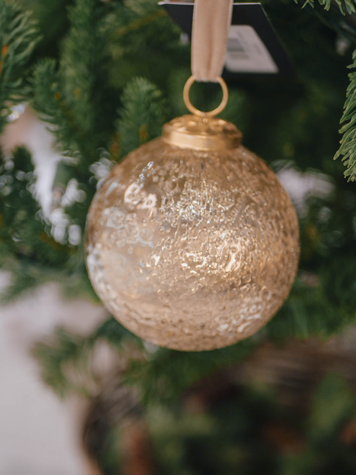 Gold glass ornament hanging on a Christmas tree