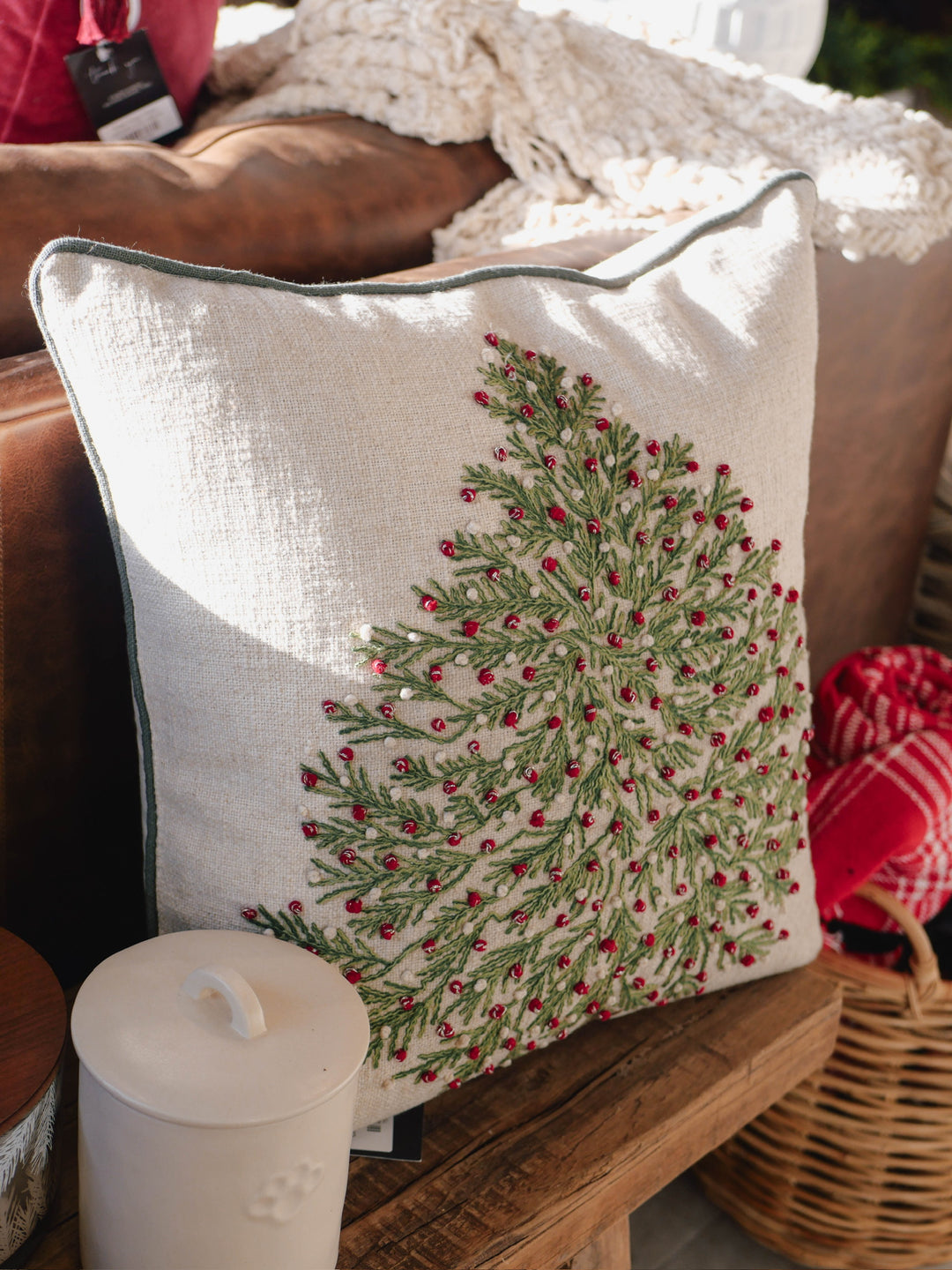 Decorative pillow with a Christmas tree design on a couch.