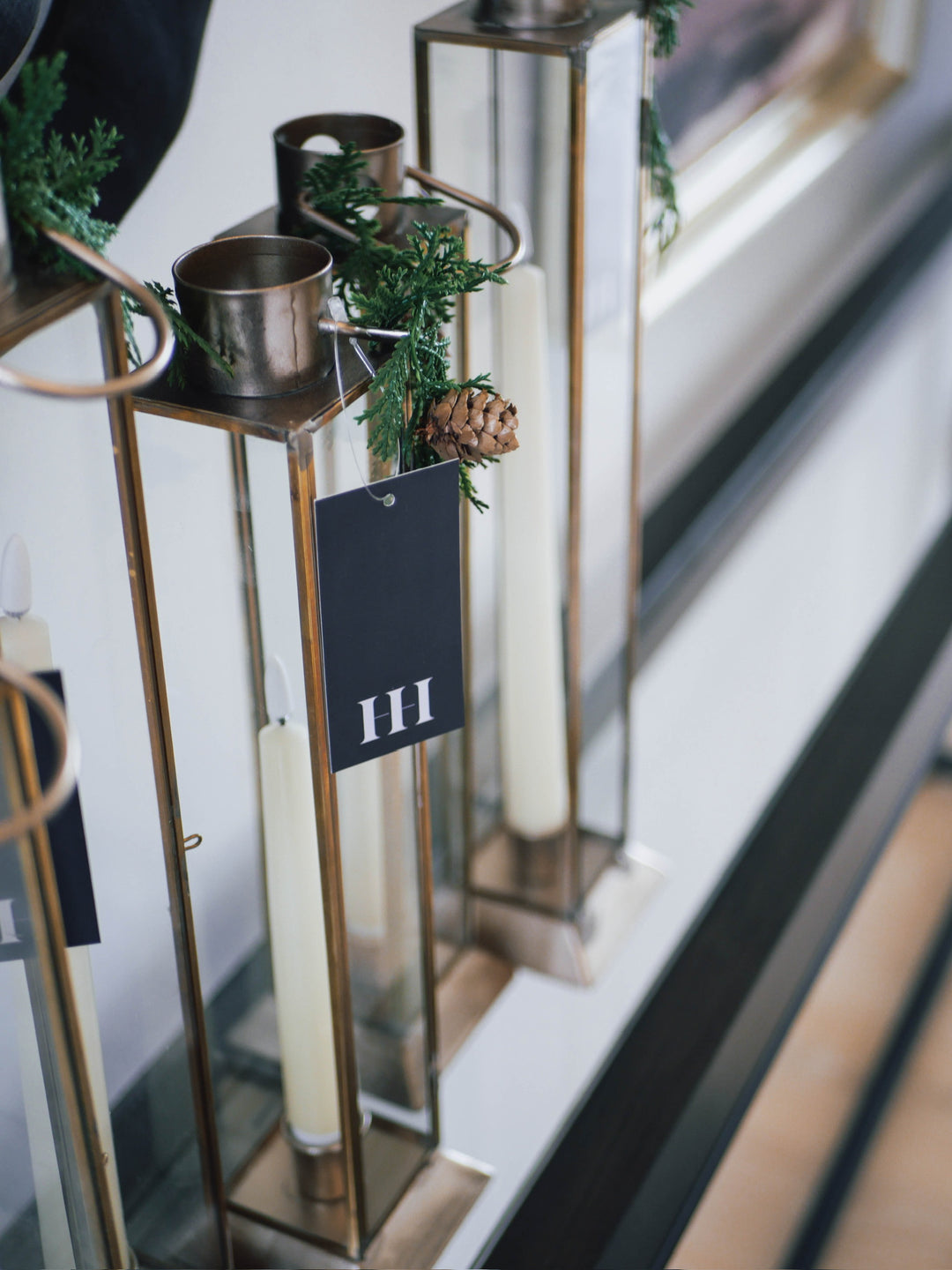 Decorative candle holders with greenery and candles on a reflective surface