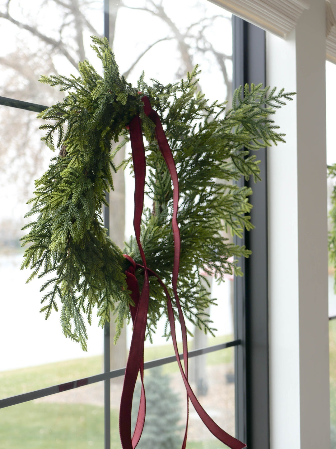 Green wreath with red ribbons hanging on a window