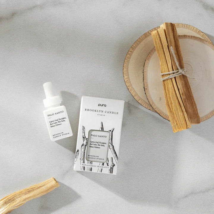Palo Santo oil bottle, packaging, and sticks on a marble surface
