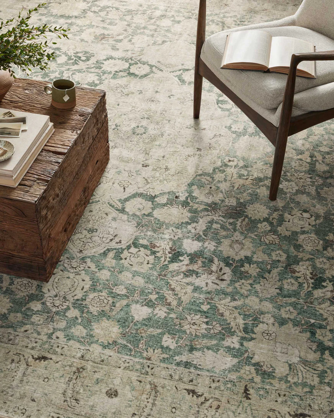 Patterned rug on a floor with a wooden coffee table and chair.