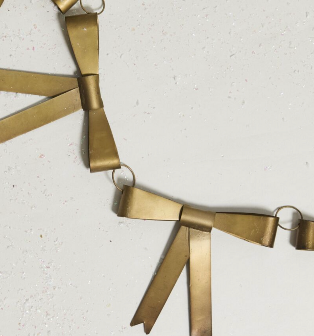 A gold-colored metal garland with classic bow decorations, suitable for holiday decor.