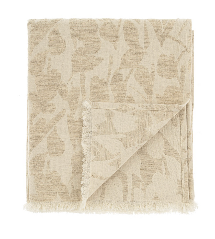 A beige throw blanket with a floral design