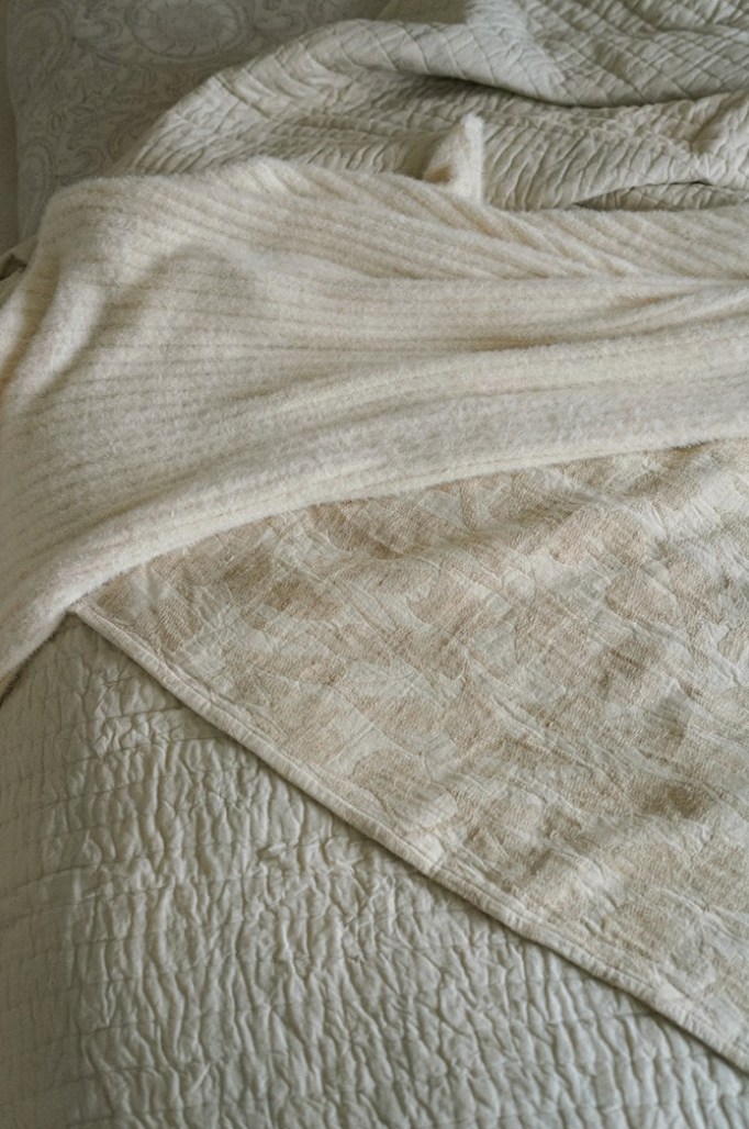 A beige throw blanket with a floral design