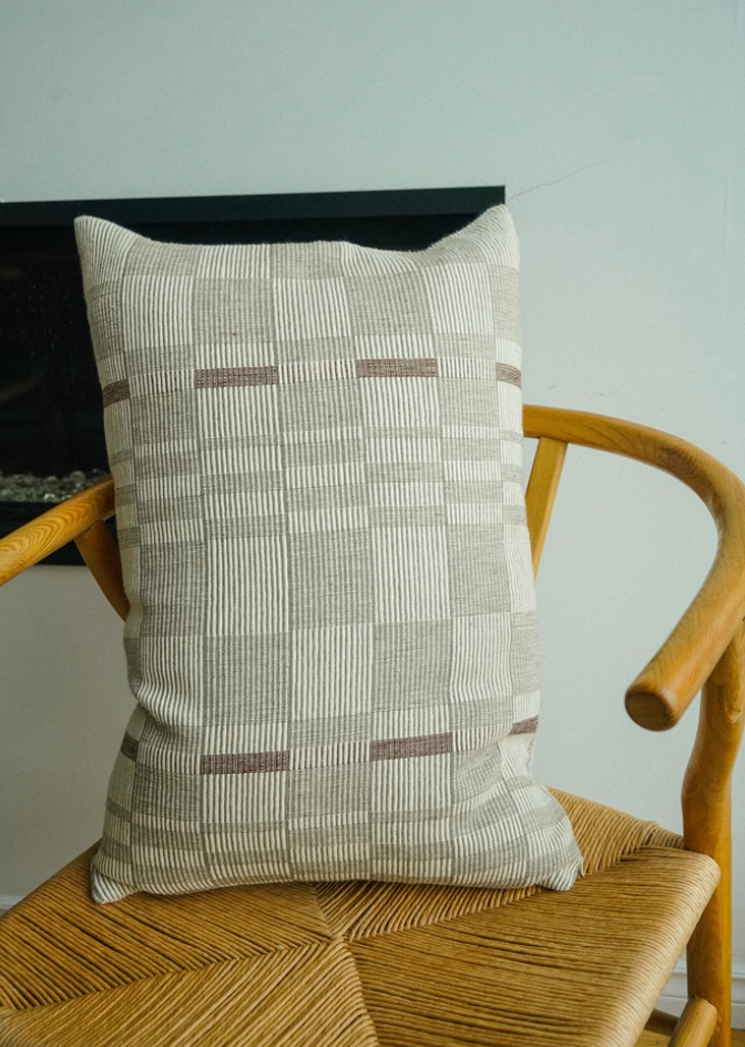 A beige and brown geometric patterned throw pillow.
