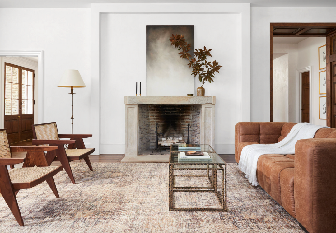 Living room with brown sofa and throw blanket, wooden chairs, and a fireplace.
