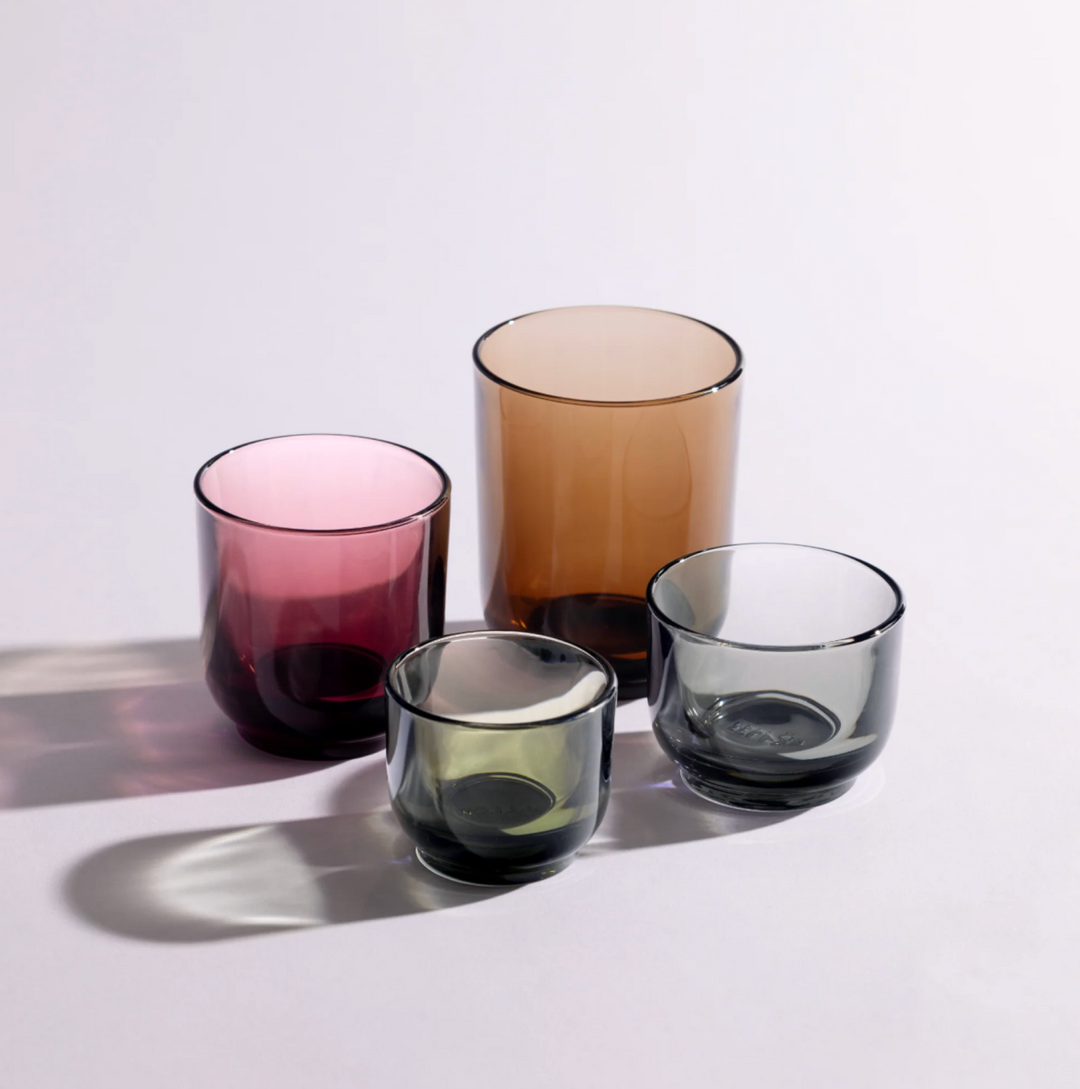 Four colorful glass Fellow coffee mugs on a light surface with a white background
