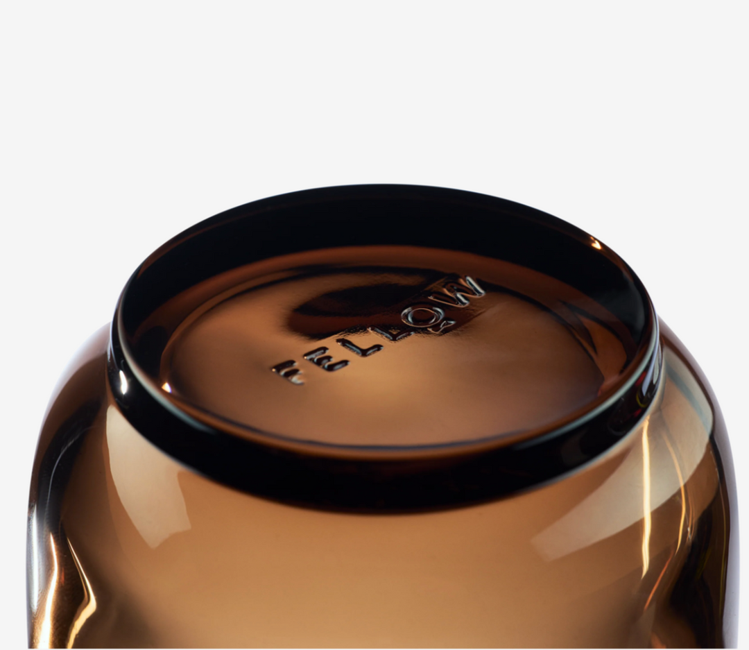 Close-up of a amber cup with 'Fellow' branding on a white background