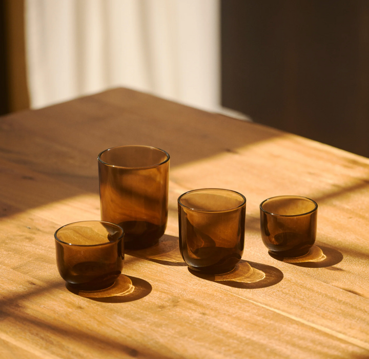 Four brown glass coffee cups on a wooden surface with soft lighting