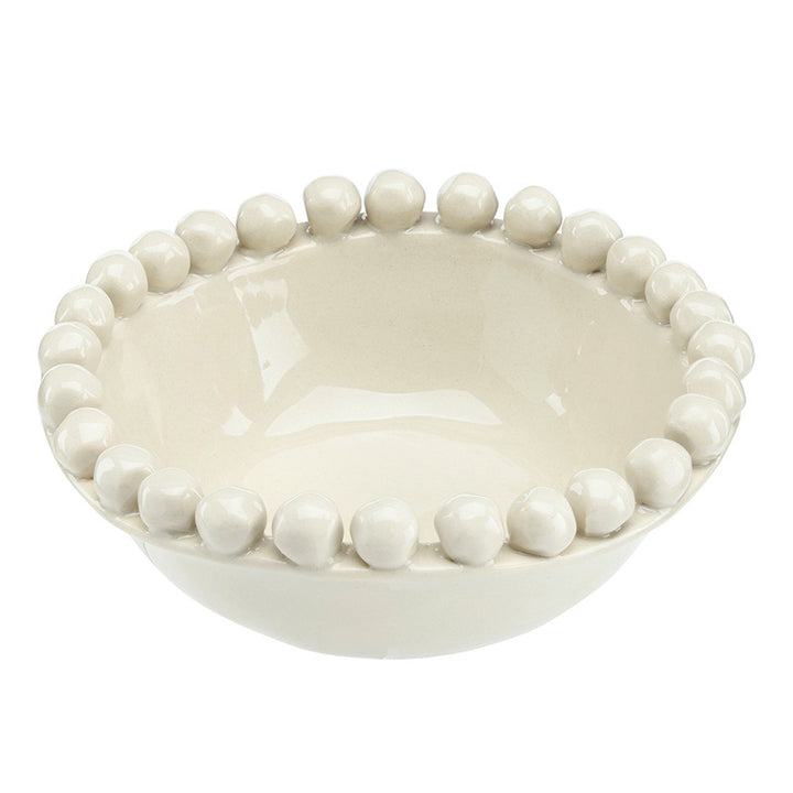 Tan ceramic bowl with bead-like embellishments on a white background