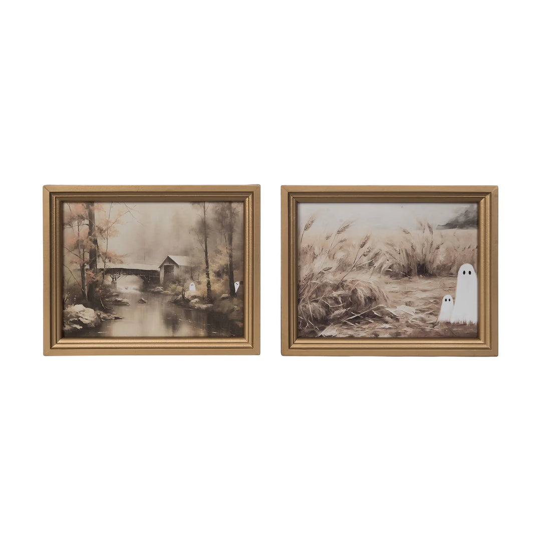 two gold frames with halloween paintings of ghosts peeking out of trees and grass
