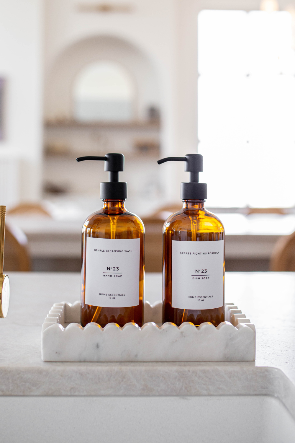 Two amber glass bottles with pump dispensers on a marble tray in a bathroom setting.