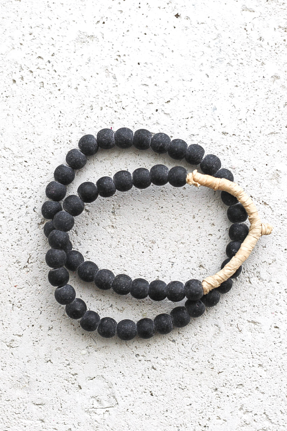 Black beaded rope with a beige cord on a light gray surface