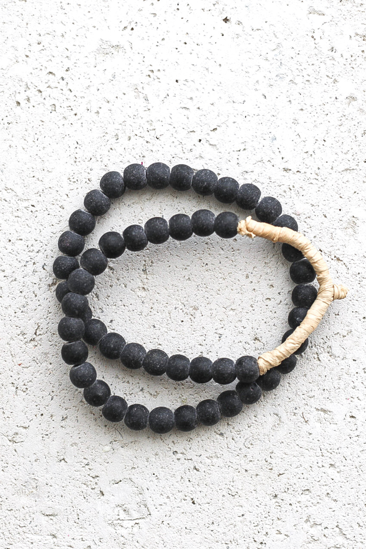 Black beaded rope with a beige cord on a light gray surface