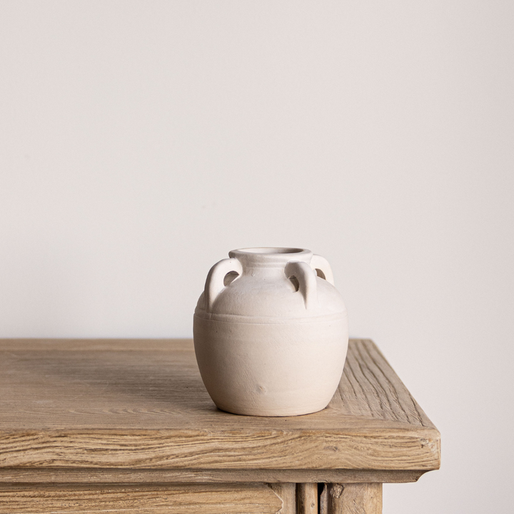White ceramic vase on a wooden table with a plain background
