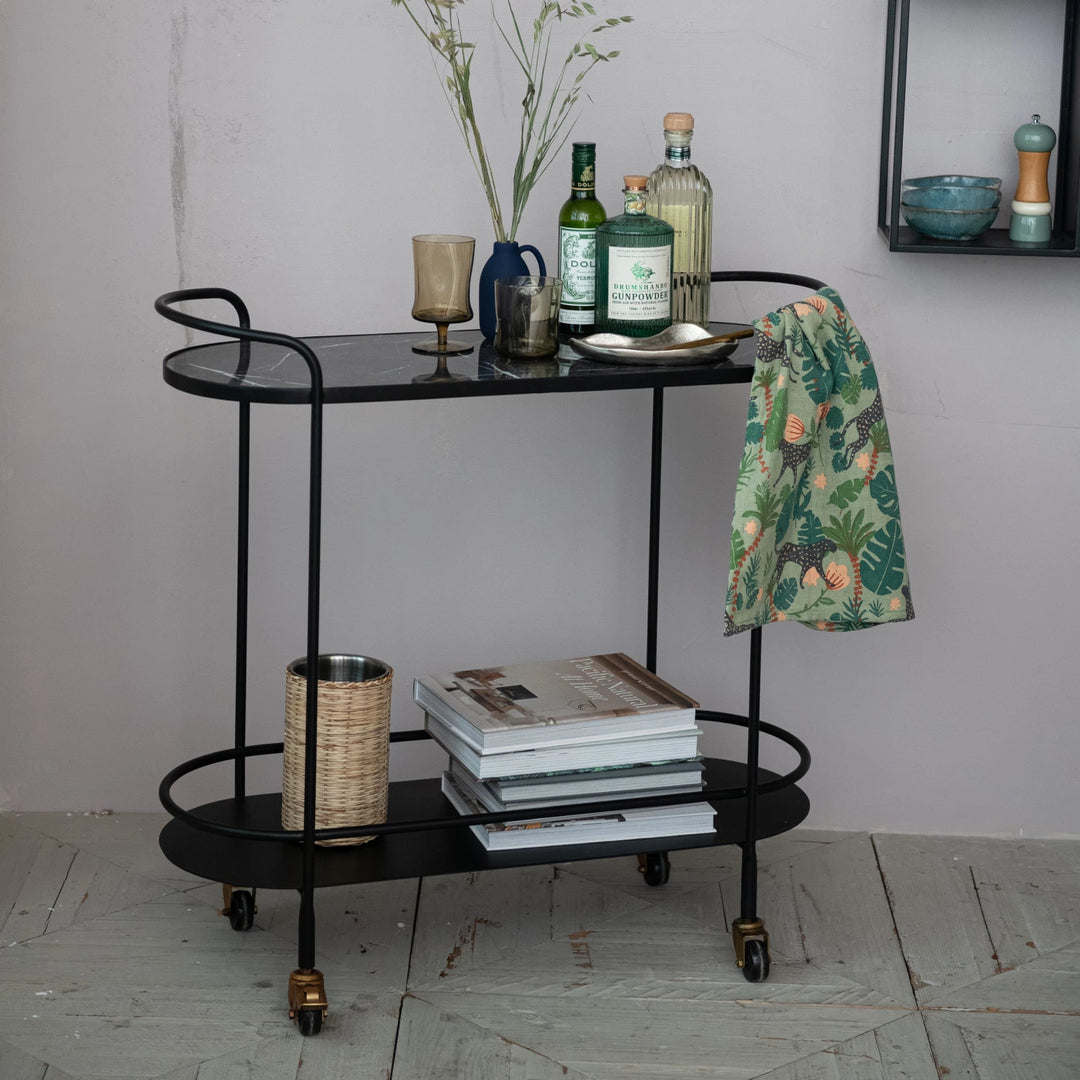black metal bar cart with glasses and books