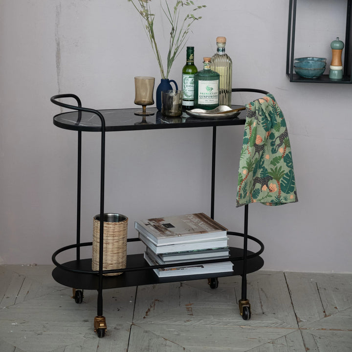 black metal bar cart with glasses and books