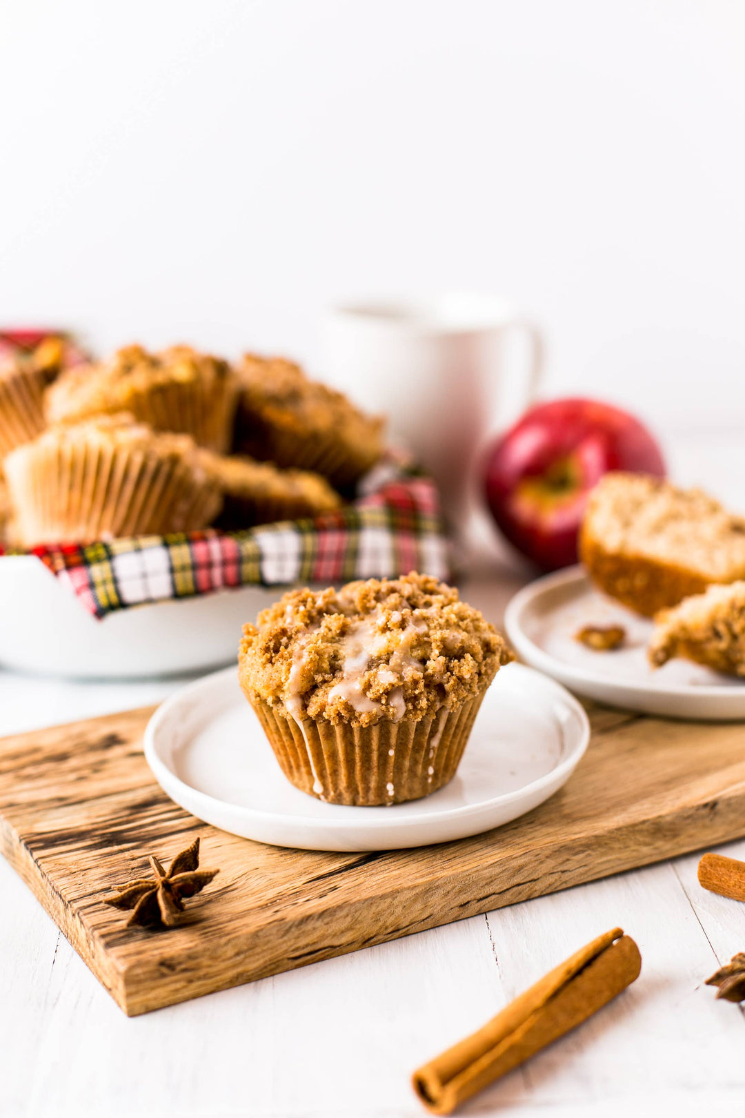Apple muffins on a wooden board with apples and cinnamon sticks in the background