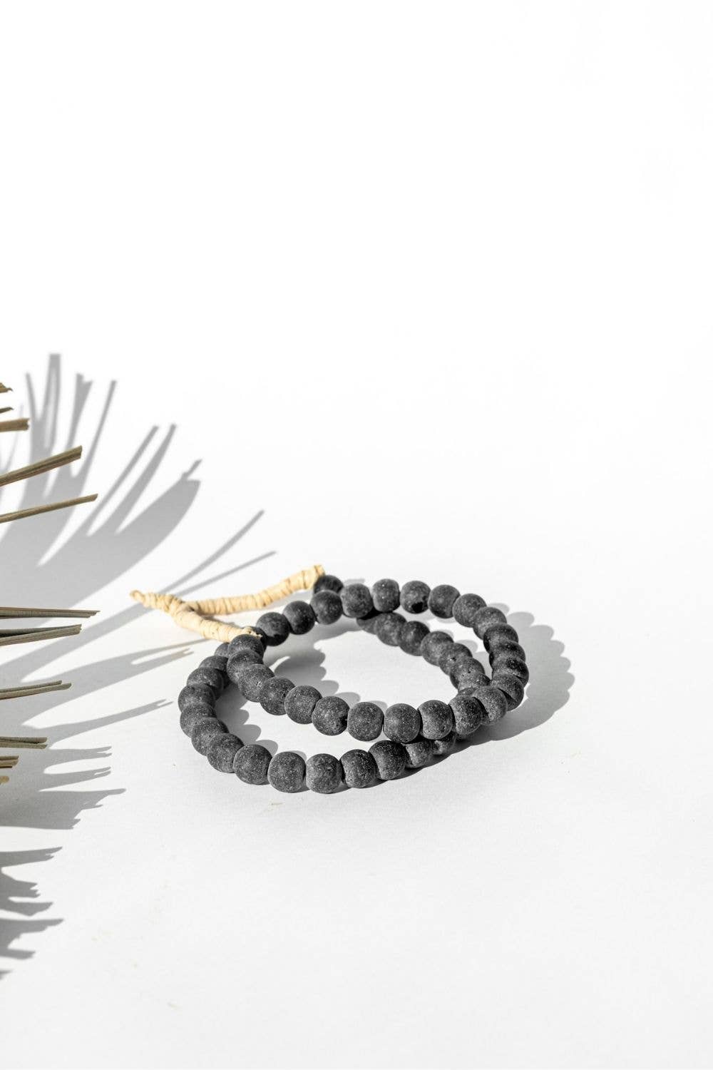 Gray beaded rope on a white surface with a light background