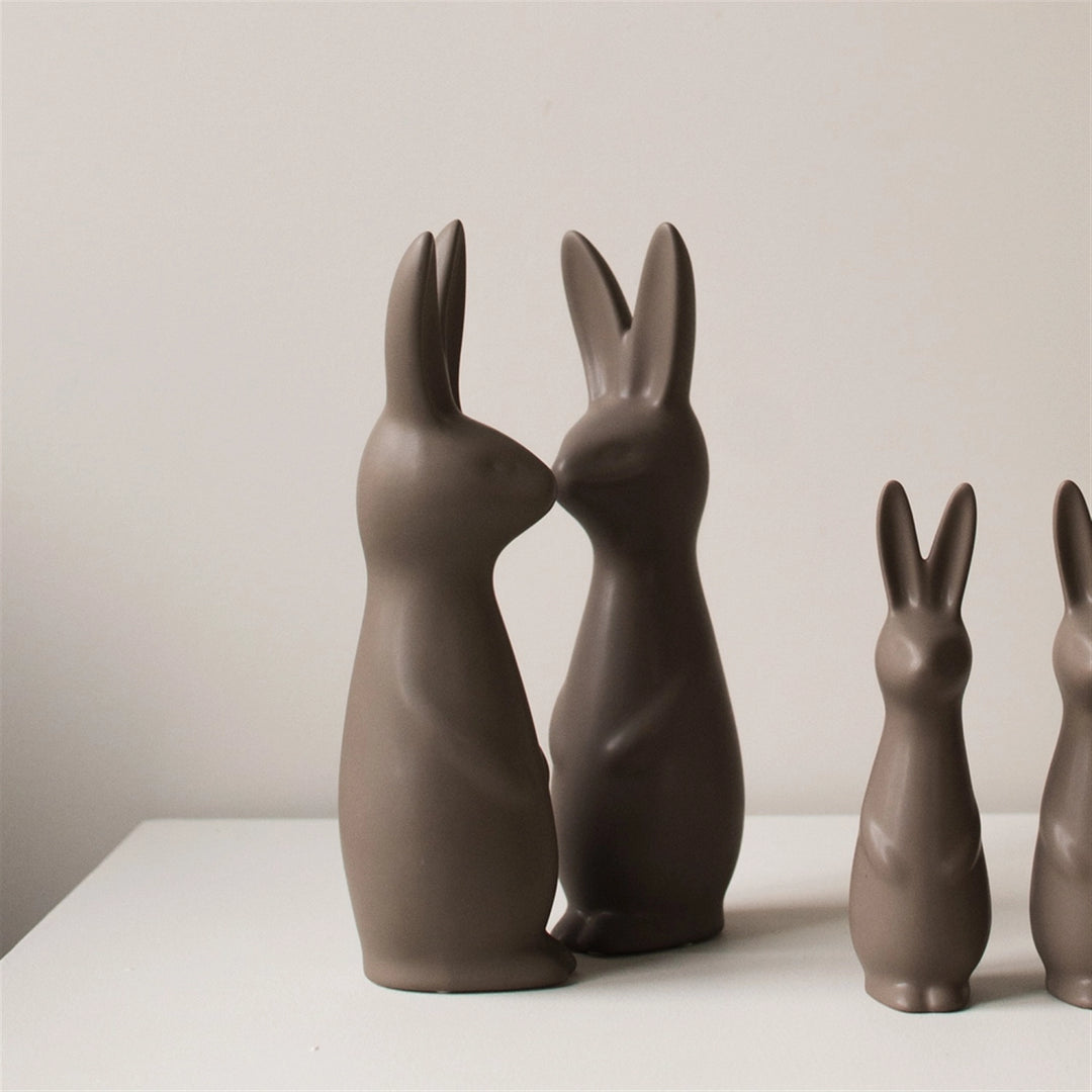 Set of brown ceramic rabbit sculptures on a white surface with a neutral background