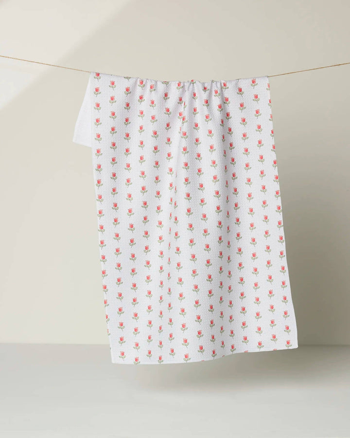 White geometry towel with red floral pattern hanging on a line against a beige background