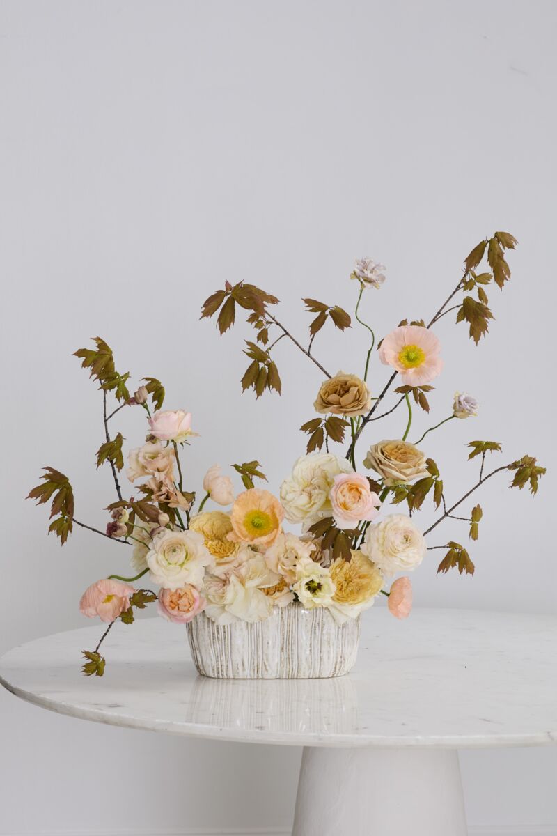 Floral arrangement in a white vase on a white table with a light gray background