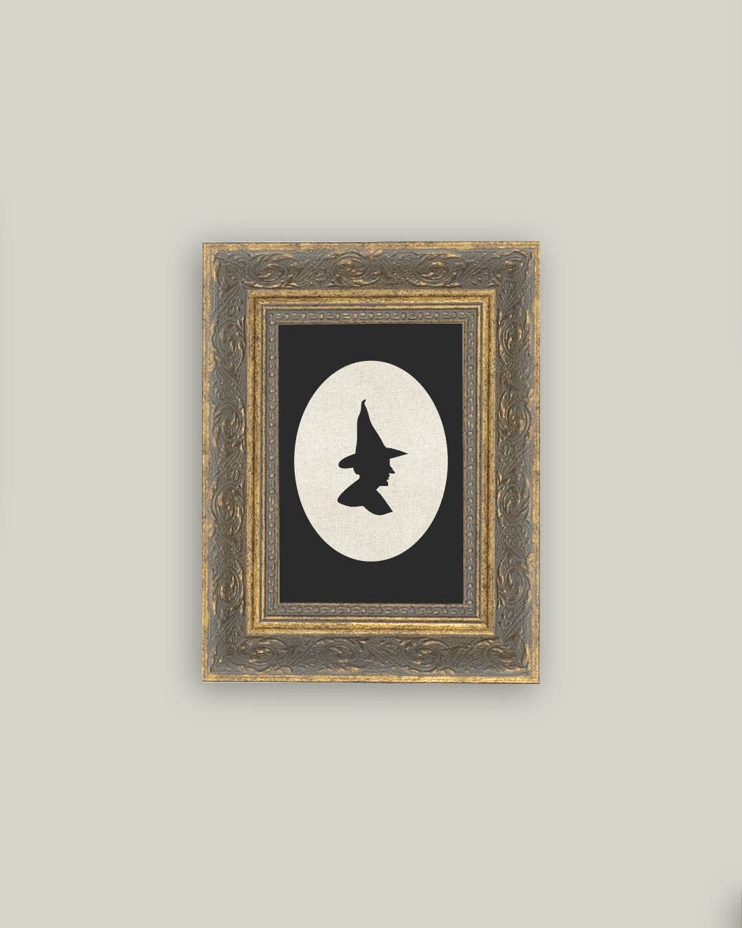 Framed artwork with a silhouette of a witch in a hat on a black background