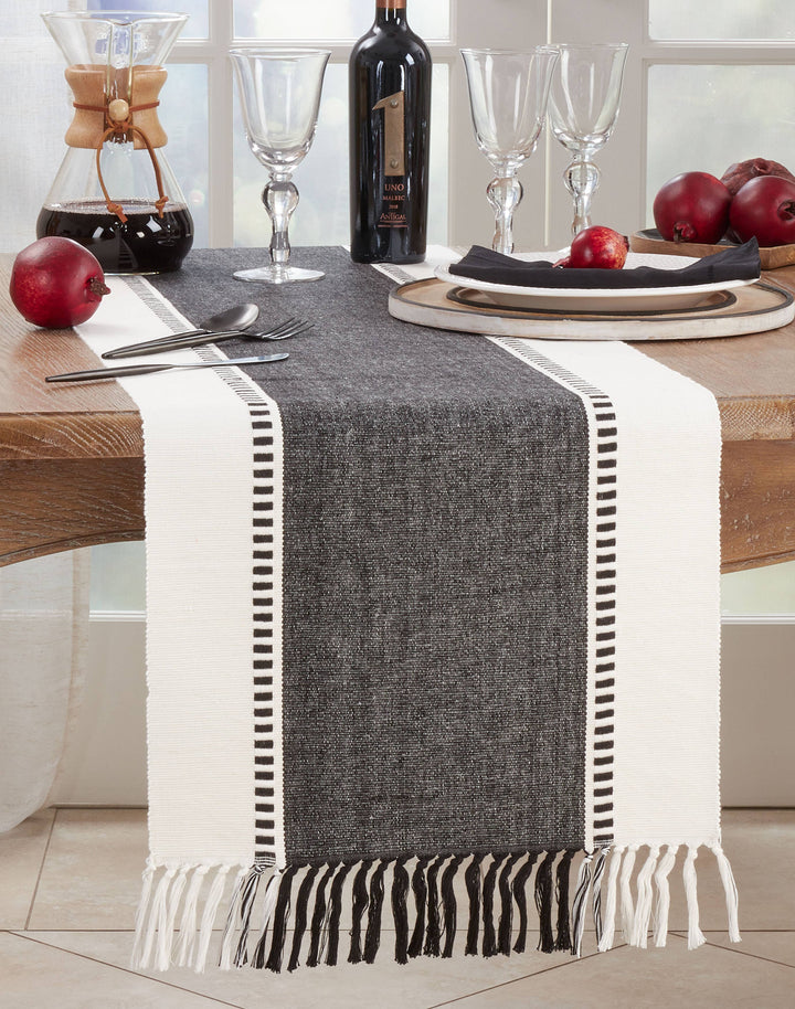 Gray table runner with white fringe on a dining table setting.