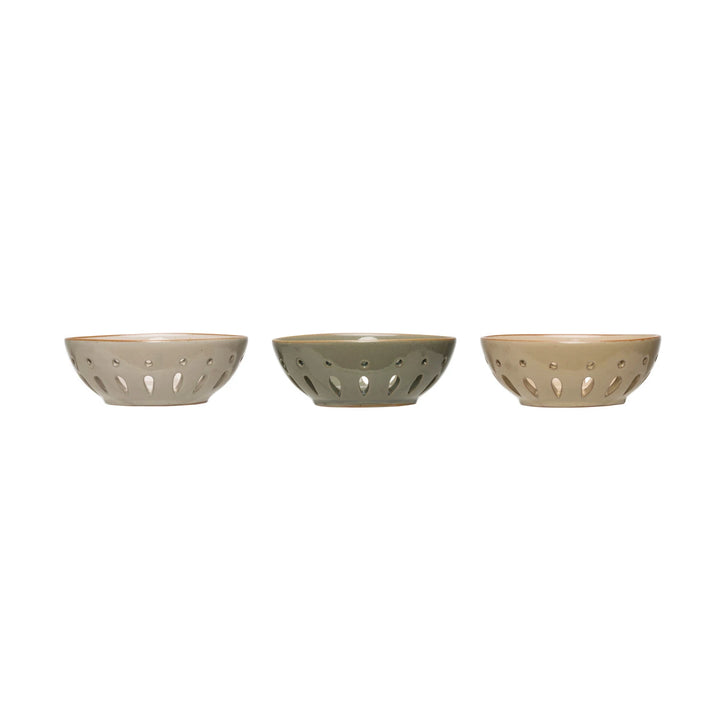 Three beige ceramic bowls with perforated designs on a white background