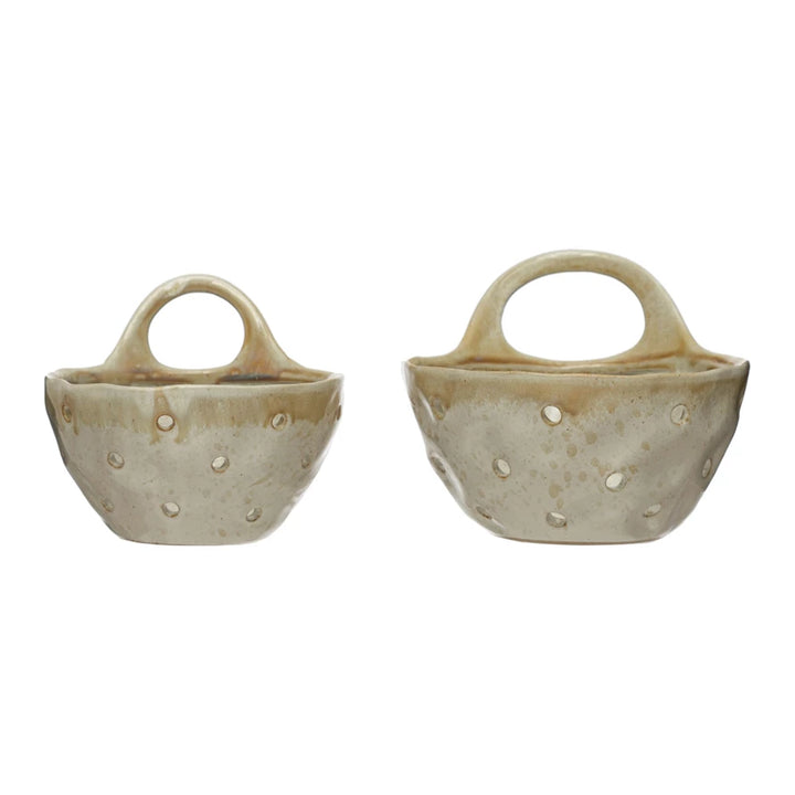 Two beige ceramic wall colanders with handles on a white background