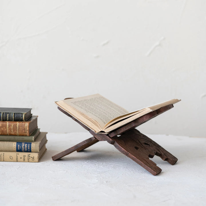 Wooden book stand with an open book on a white surface
