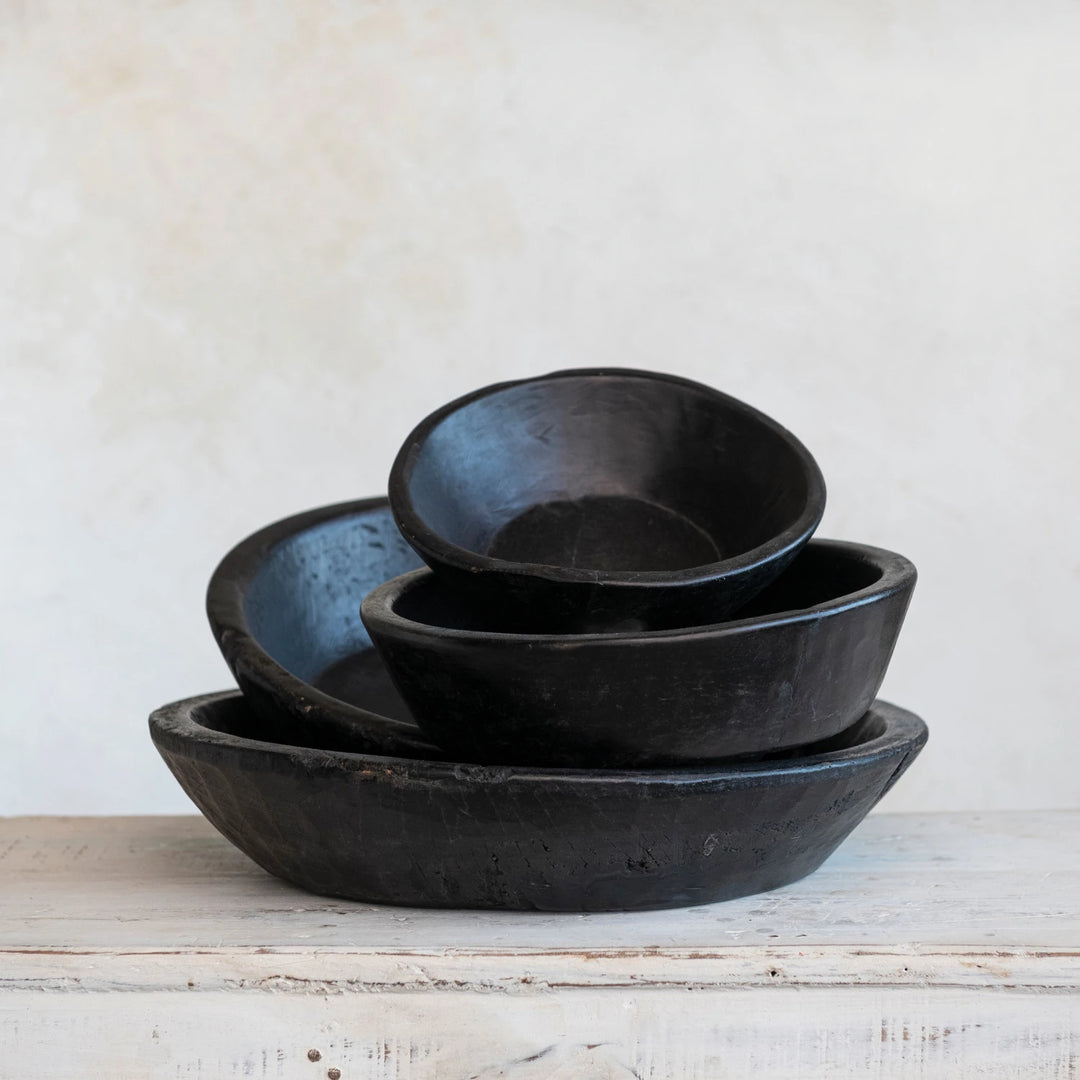 Set of black ceramic bowls on a wooden surface