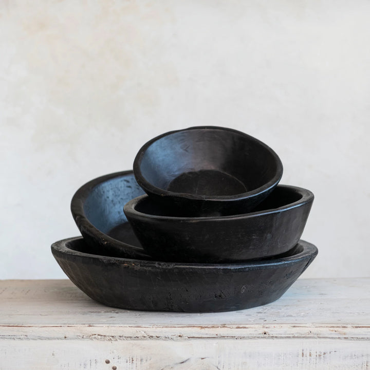 Set of black ceramic bowls on a wooden surface