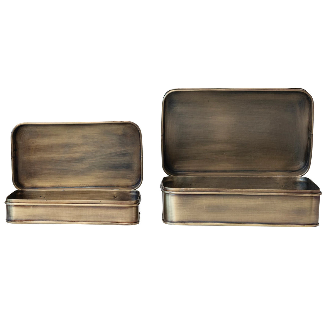 Two brass-colored metal boxes with lids on a white background