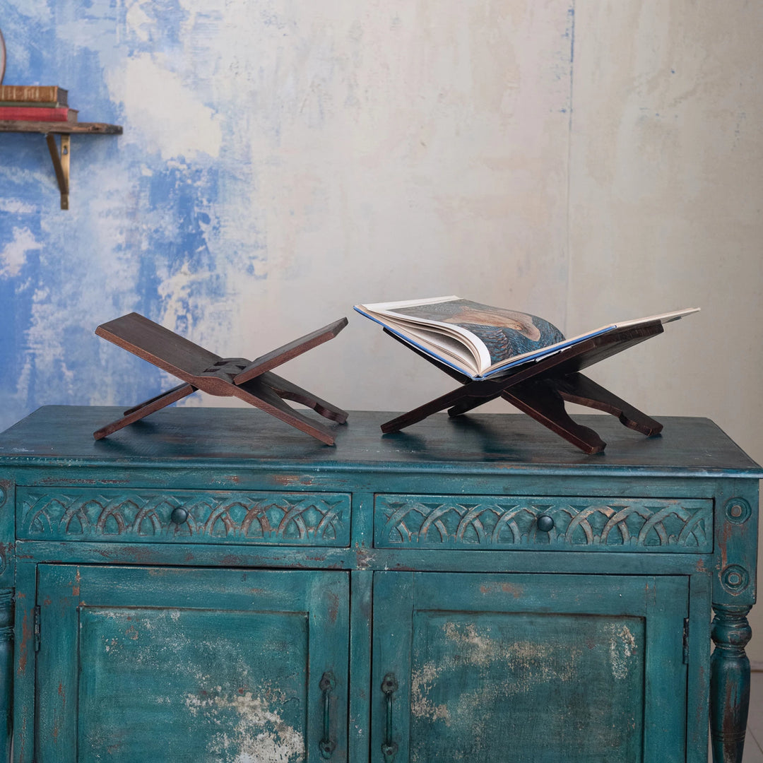 Two wooden book stands on a rustic blue cabinet