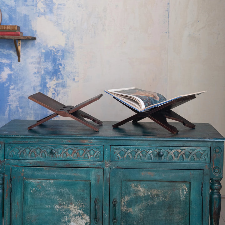 Two wooden book stands on a rustic blue cabinet