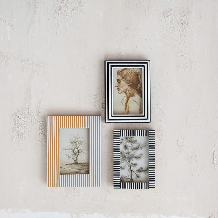 Three framed artworks on a textured wall.