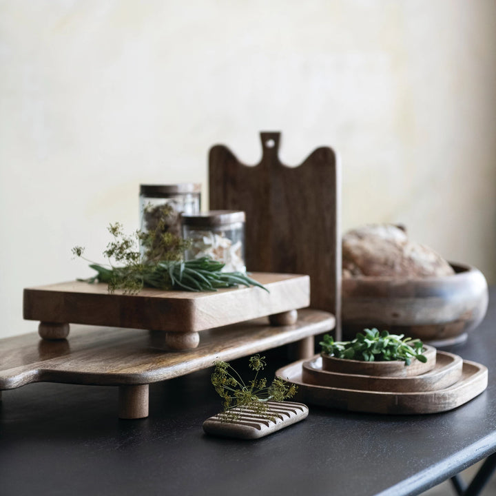 Wooden cutting board with jars and plants on a dark surface
