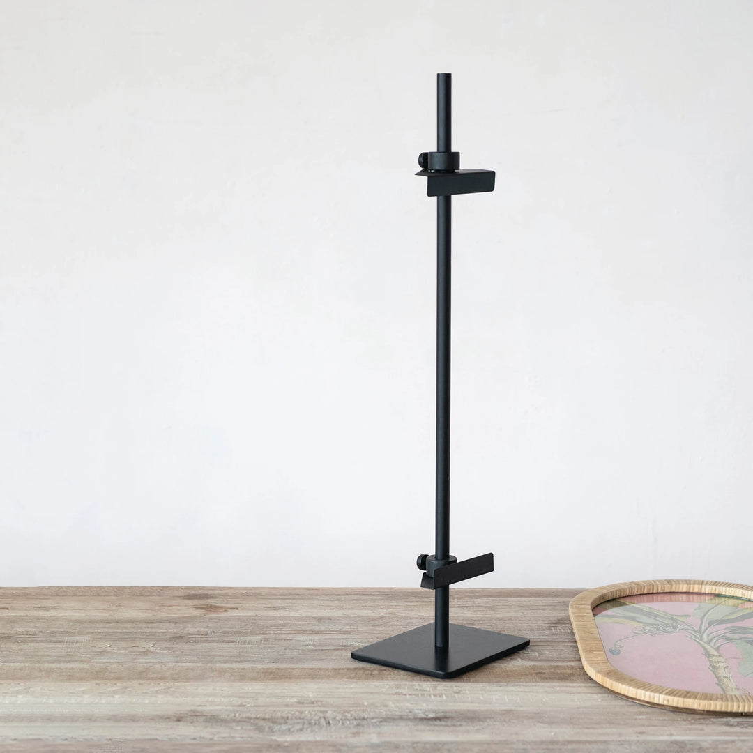 Black adjustable stand on a wooden surface with a white background