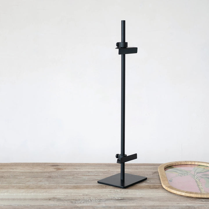 Black adjustable stand on a wooden surface with a white background