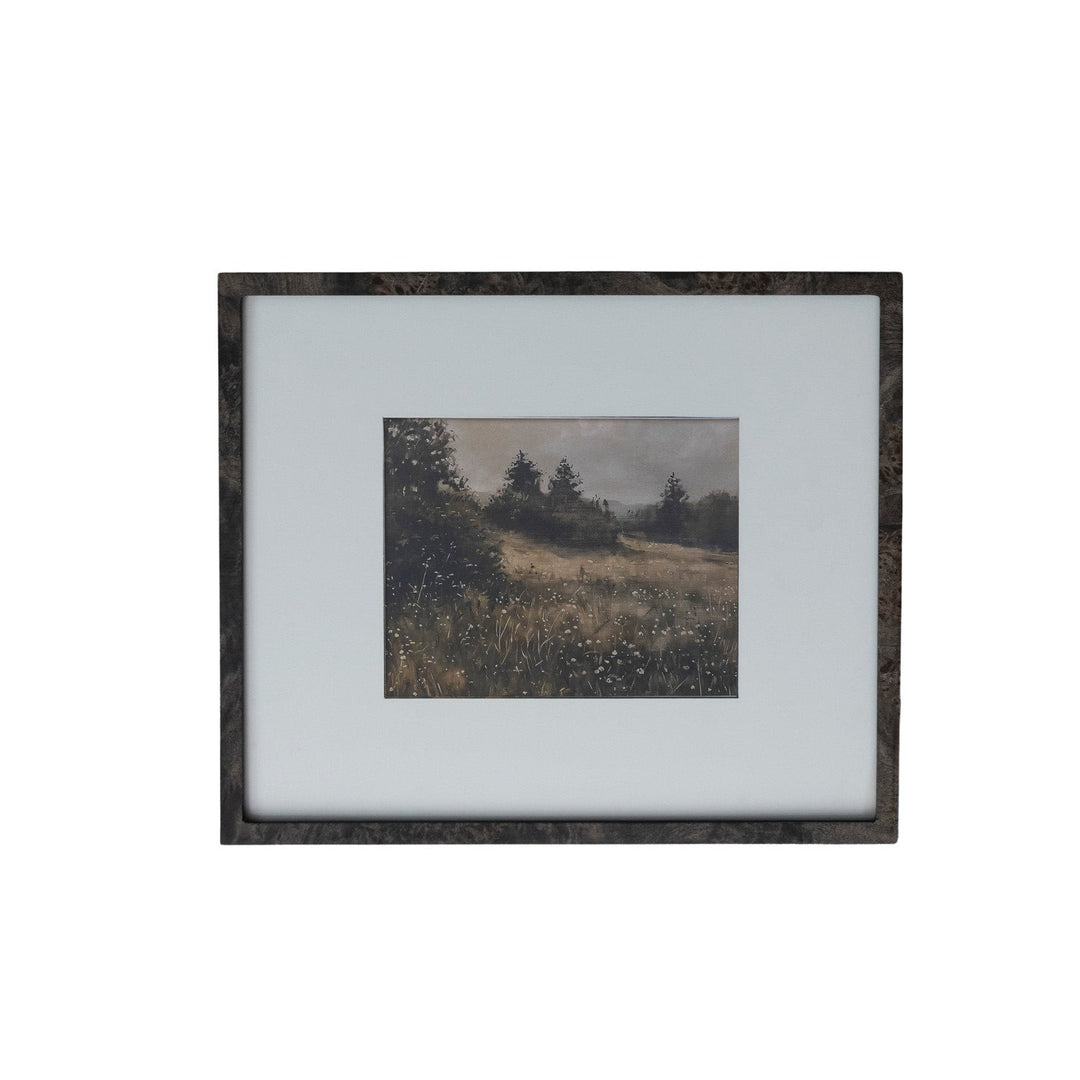A framed landscape art print featuring a muted, impressionistic scene of a grassy field and trees under a cloudy sky, set in a dark textured frame with a wide white mat border.