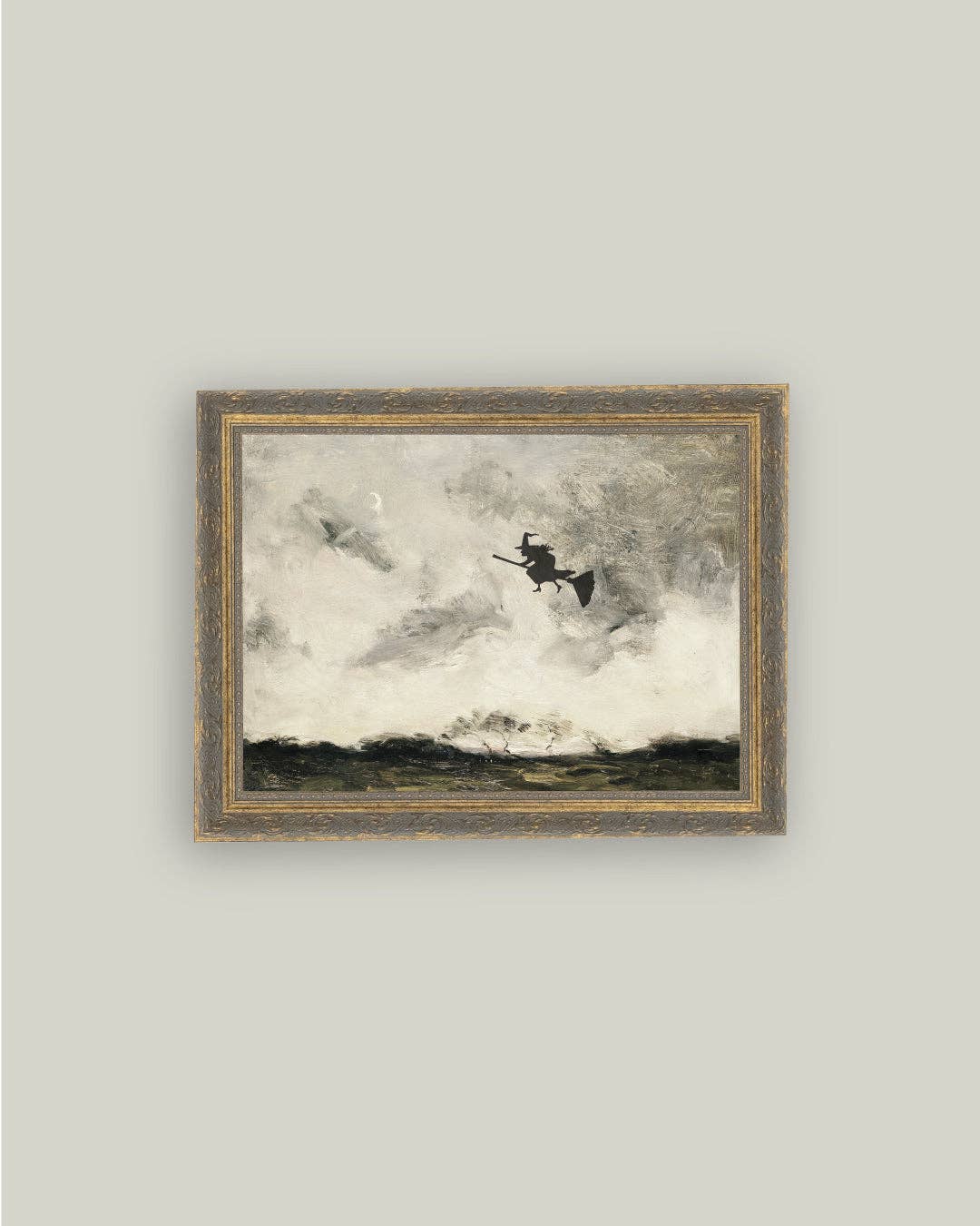 Framed artwork of a witch flying over clouds on a gray wall