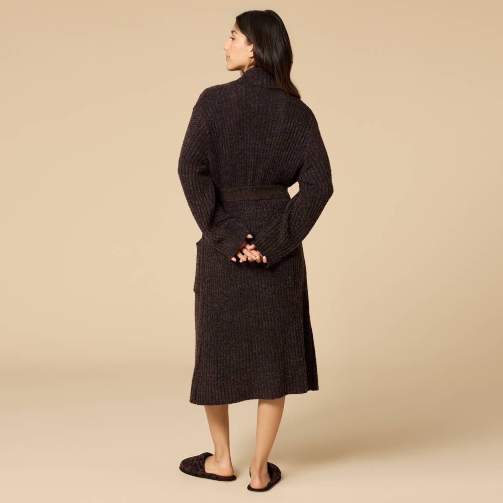 Woman wearing a dark brown ribbed knit robe against a beige background