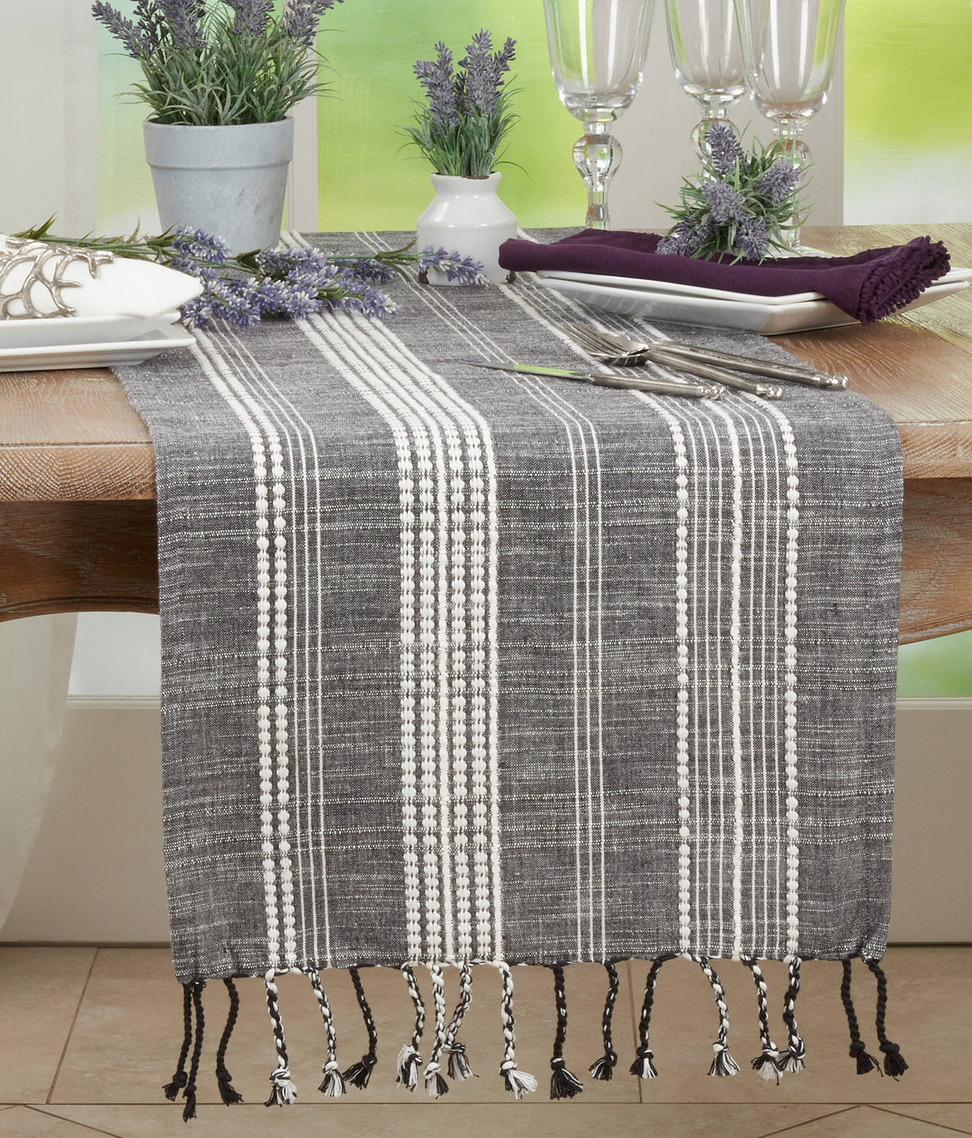 Gray and white plaid table runner with tassels on a dining table.