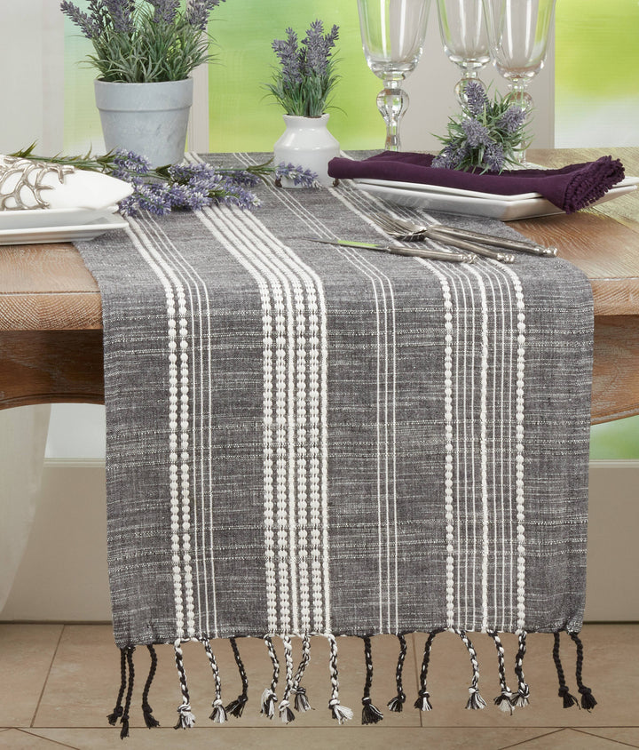 Gray and white plaid table runner with tassels on a dining table.